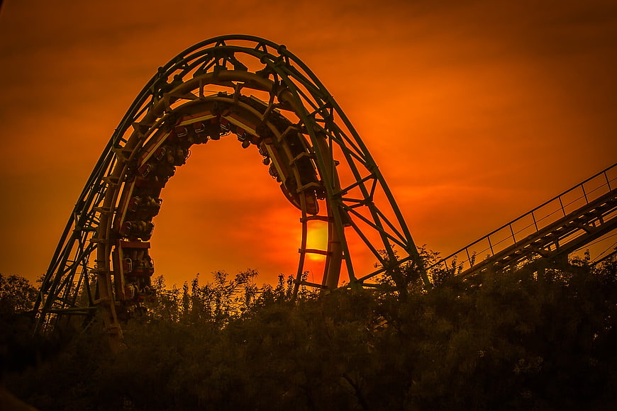 Roller Coaster Loop Silhouette Against Dramatic Orange Sunset Sky