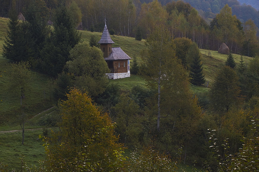 Small wooden chapel on a green mountain hillside