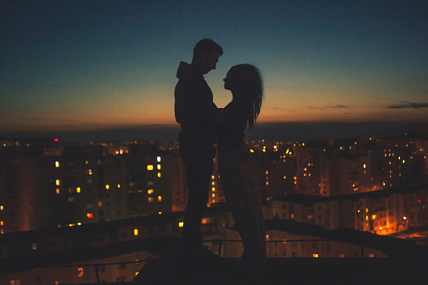 Silhouette of romantic couple embracing on rooftop at dusk