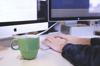 Person Typing on Keyboard with Green Coffee Mug