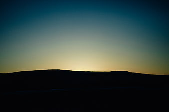 Silhouette of rolling hills against a twilight sky gradient