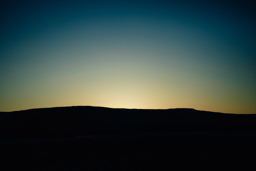 Silhouette of rolling hills against a twilight sky gradient