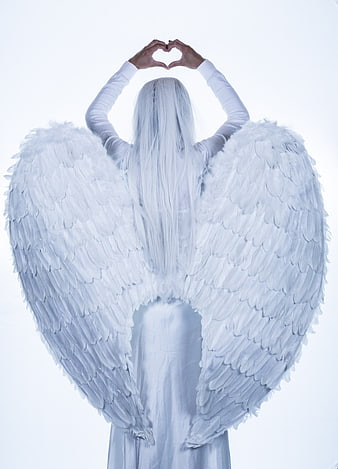 Woman with white angel wings making heart shape