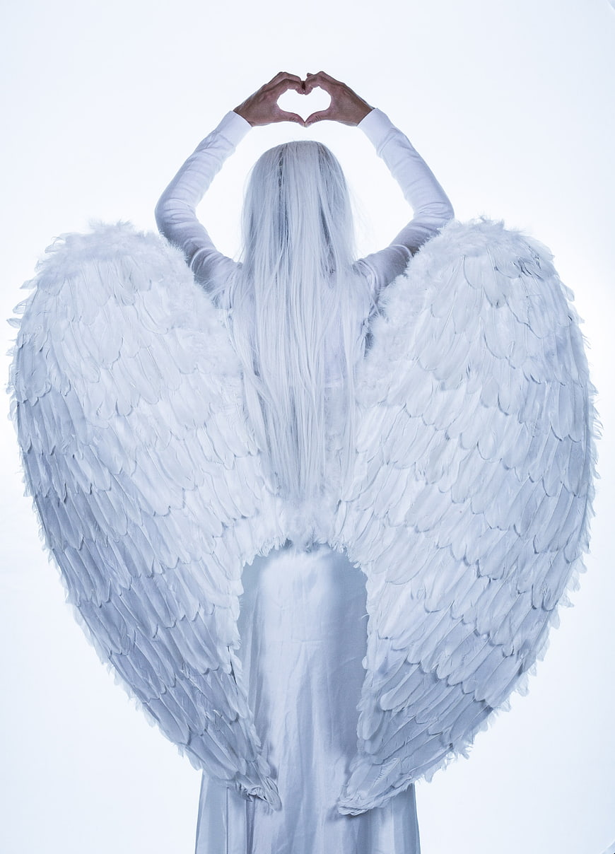 Woman with white angel wings making heart shape