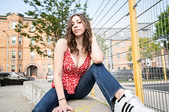 Young woman in red floral top sitting on urban ledge