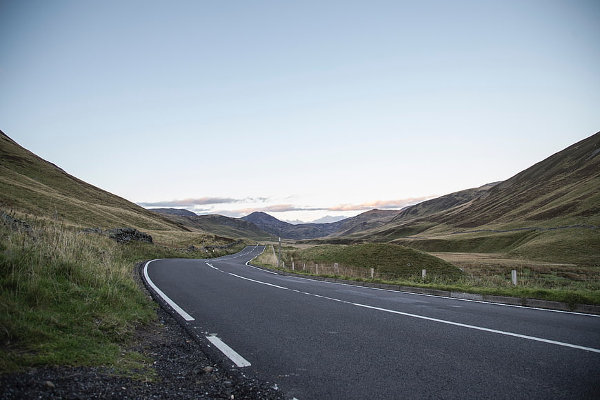 Winding Country Road Through Rolling Green Hills at Dusk