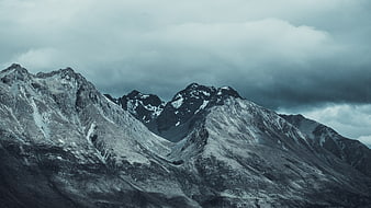 Dramatic Snow-Capped Mountain Peaks Under Stormy Clouds