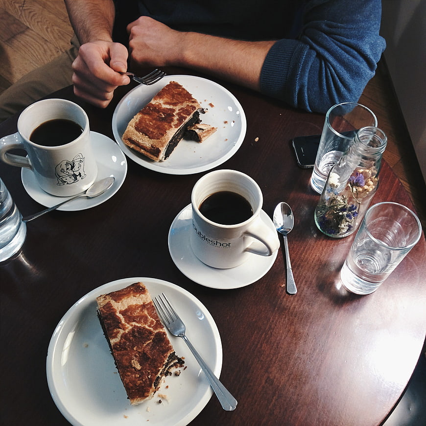 Overhead view of coffee and poppy seed strudel on wooden table