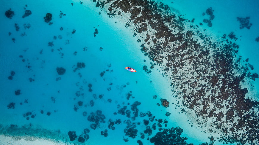 Aerial view of a lone boat in turquoise ocean waters