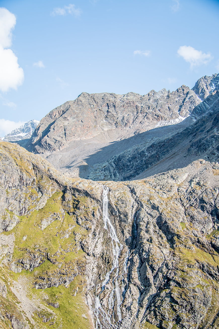 Majestic mountain landscape with cascading waterfall and blue sky