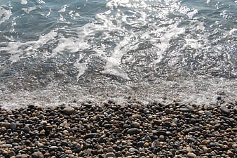 Ocean waves crashing on a pebble beach with sparkling water