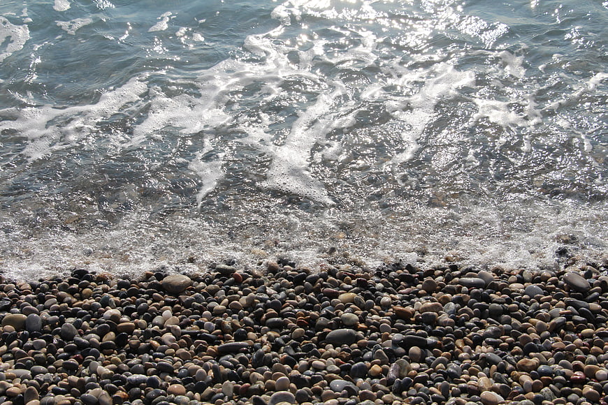 Ocean waves crashing on a pebble beach with sparkling water