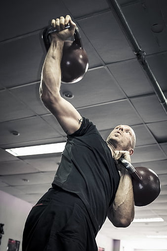 Man performing kettlebell side press in gym
