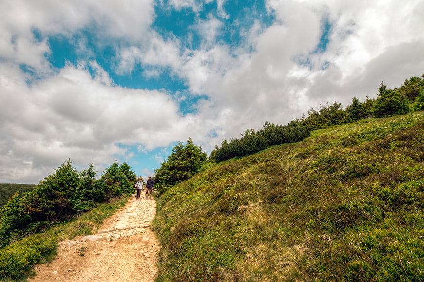 Hikers Walking on Mountain Trail Under Blue Sky