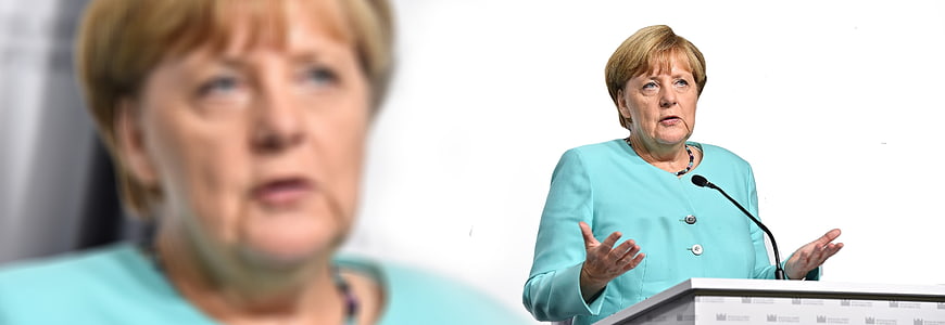 Angela Merkel Speaking at Podium in Turquoise Jacket