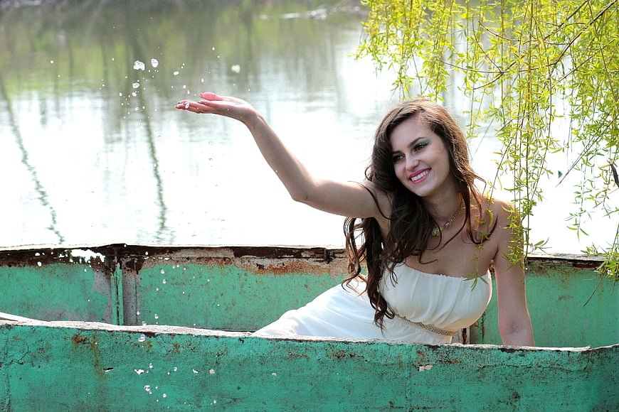 Woman in White Dress Splashing Water in Rusty Boat