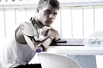 Young man with robotic arm leaning on table