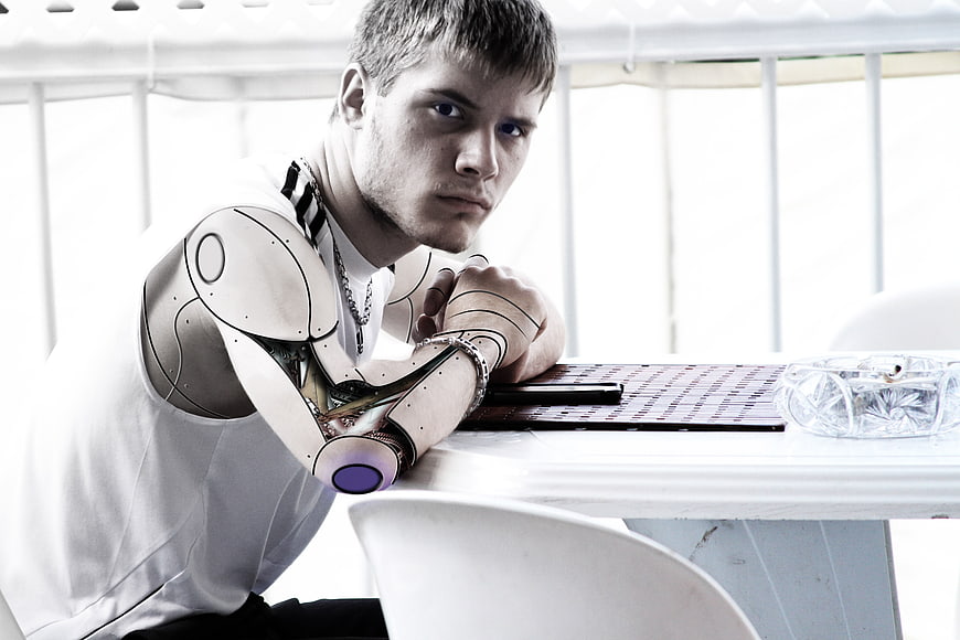 Young man with robotic arm leaning on table