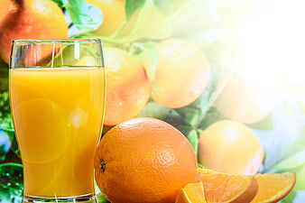 Fresh Orange Juice in Glass with Whole and Sliced Oranges