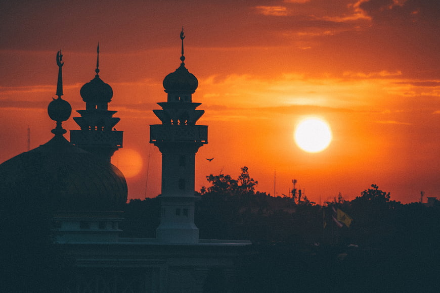 Silhouette of Mosque Minarets Against Vibrant Orange Sunset Sky