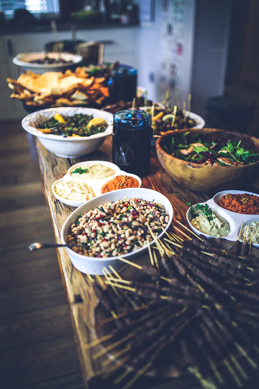 Rustic wooden table spread with healthy food, salads, and skewers