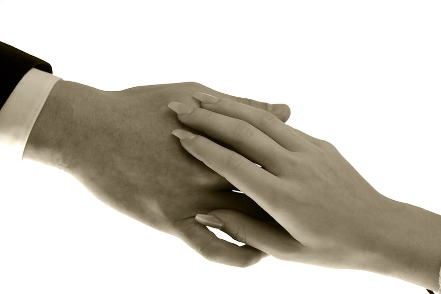 Close-up of a woman's hand gently resting on a man's hand