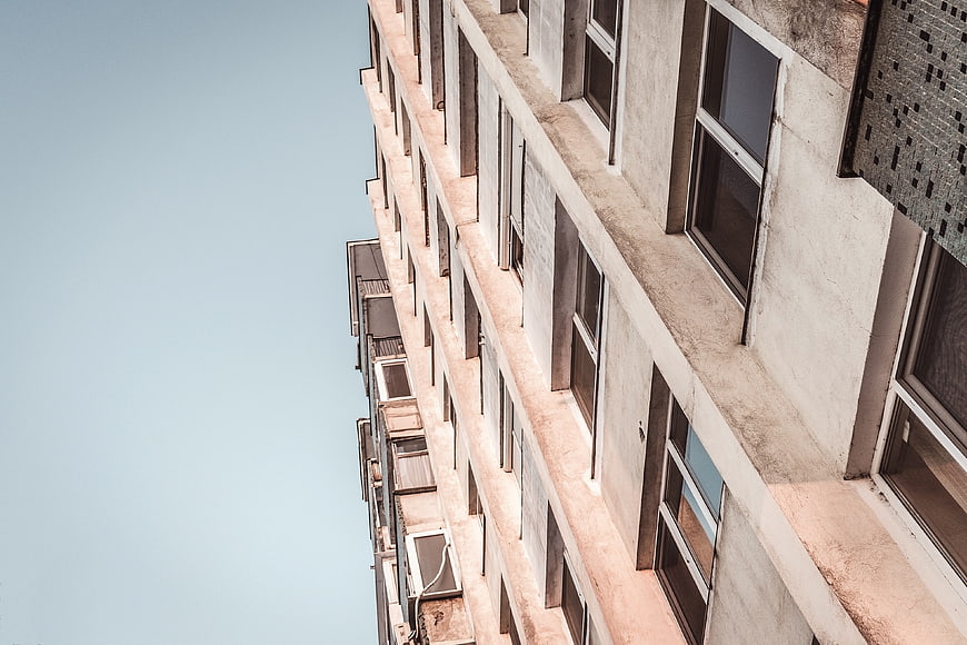 Low angle view of concrete apartment building against blue sky