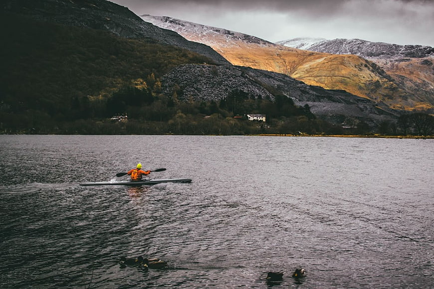 Kayaker on Lake with Snowy Mountains Background