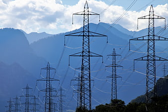 High Voltage Power Lines Silhouetted Against Blue Mountain Range
