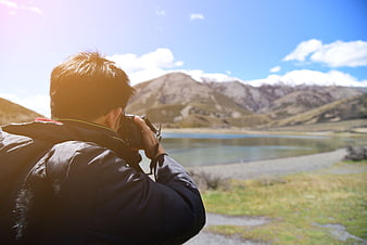 Photographer capturing mountain lake landscape with camera
