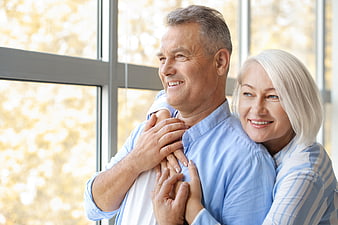 Happy Senior Couple Embracing Indoors by Window