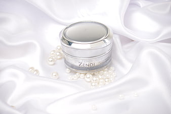 Luxury skincare cream jar on white silk with pearls
