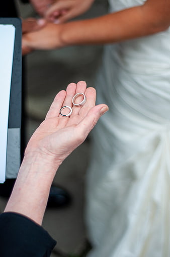 Close-up of wedding rings held in hand during ceremony