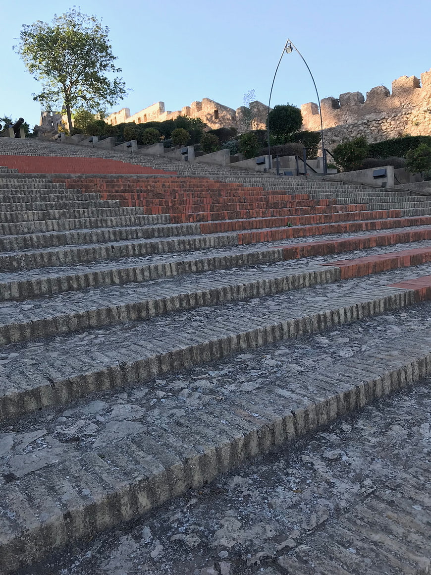 Ancient stone amphitheater steps with historic ruins background