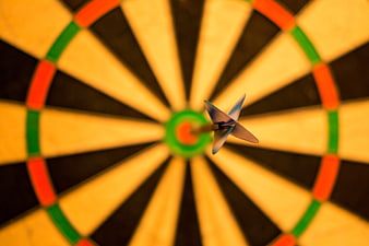 Dart hitting bullseye on dartboard close up