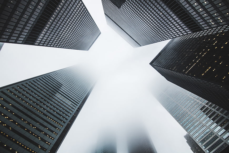 Low-angle view of skyscrapers disappearing into thick fog