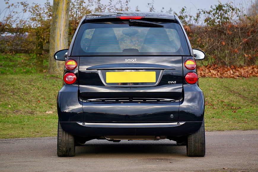 Rear view of black Smart car parked on road