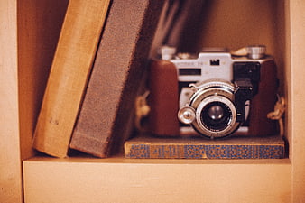 Vintage Film Camera on Wooden Bookshelf with Old Books