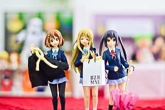 Three anime schoolgirl figures holding shopping bag and umbrella at convention