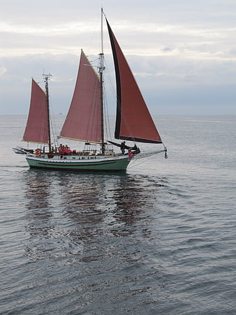 Traditional Schooner with Red Sails Sailing on Calm Ocean