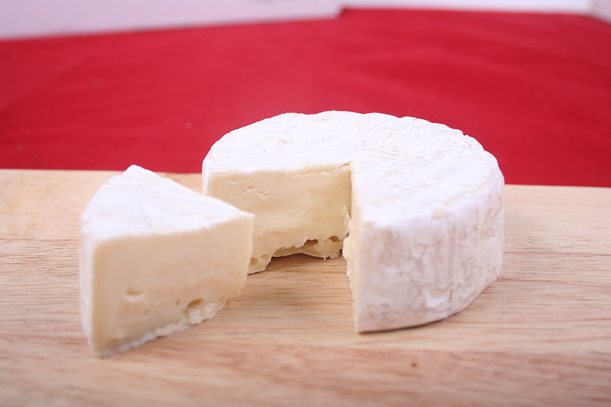 Fresh Brie Cheese Wheel with Slice on Wooden Board