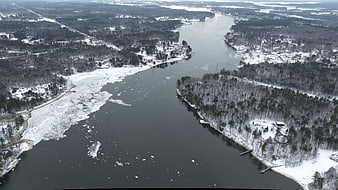 Aerial view of frozen river winding through snowy winter forest