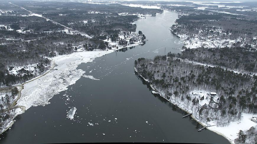 Aerial view of frozen river winding through snowy winter forest
