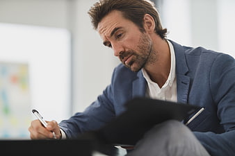 Focused businessman writing on clipboard in office