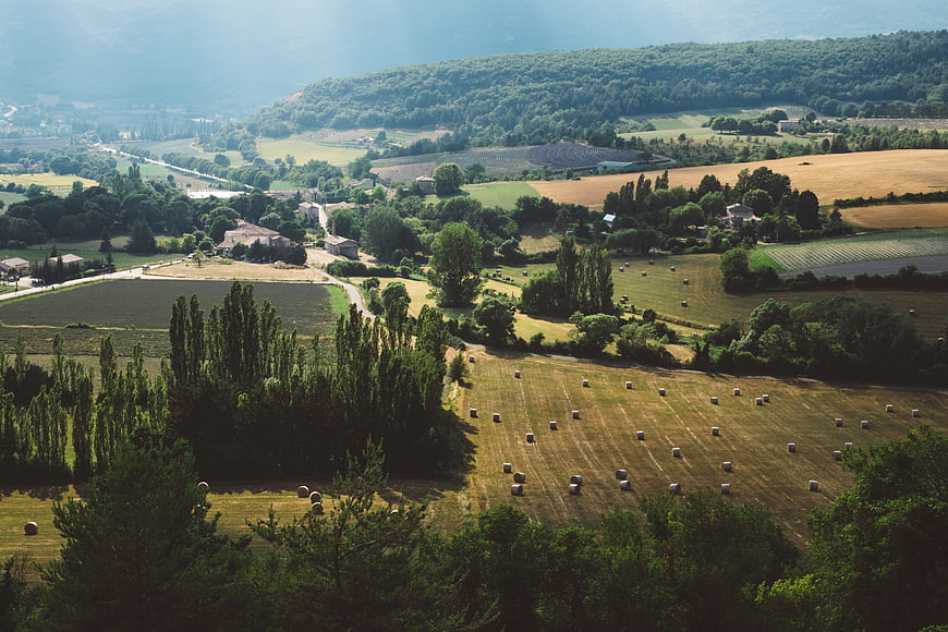 Aerial View of Rolling Countryside with Hay Bales and Farmhouses