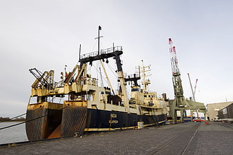 Rusty fishing vessel Nida docked at industrial port