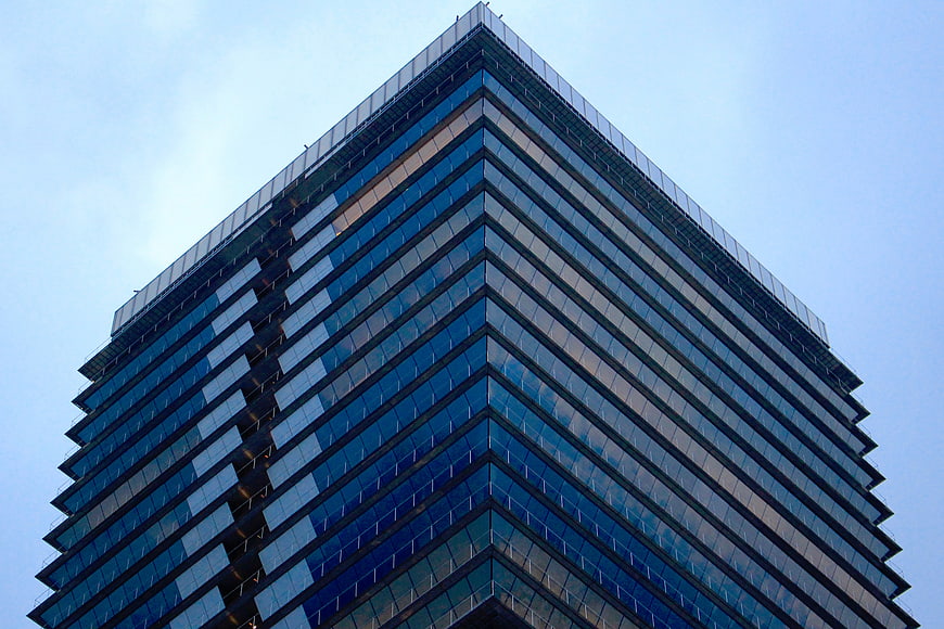 Low angle view of modern glass skyscraper against blue sky