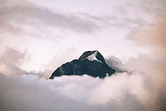 Snow-capped mountain peak emerging from clouds