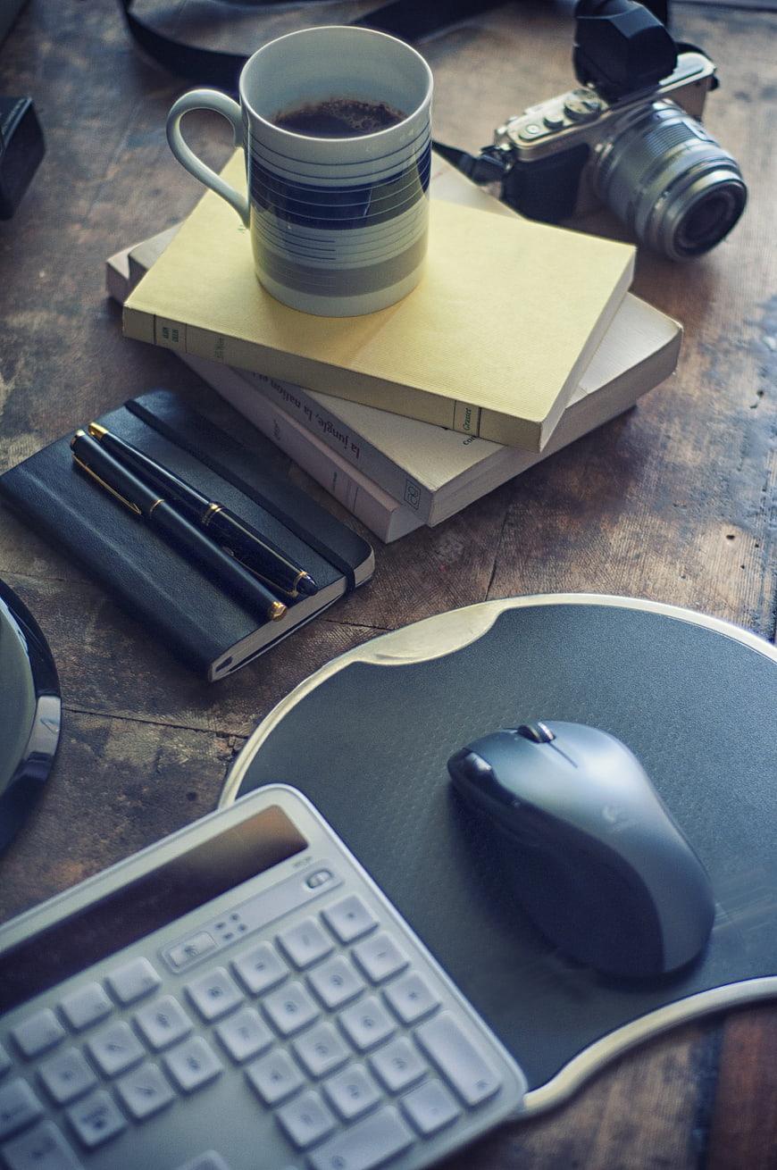Creative workspace with coffee, camera, and books on wooden desk
