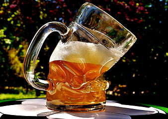 Deformed Glass Beer Mug With Amber Liquid On Outdoor Table
